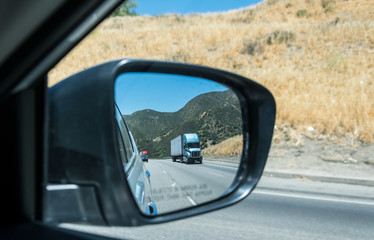 Freight traffic in the USA. High-speed highway and cars and Los Angeles County. View in the side mirror