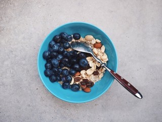 Healthy breakfast in a blue bowl. Oatmeal with blueberries and nut mix. Healthy food concept. Top view, side view. Space for text.