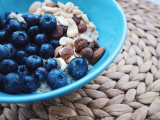 Healthy breakfast in a blue bowl. Oatmeal with blueberries and nut mix. Healthy food concept. Top view, side view. Space for text.