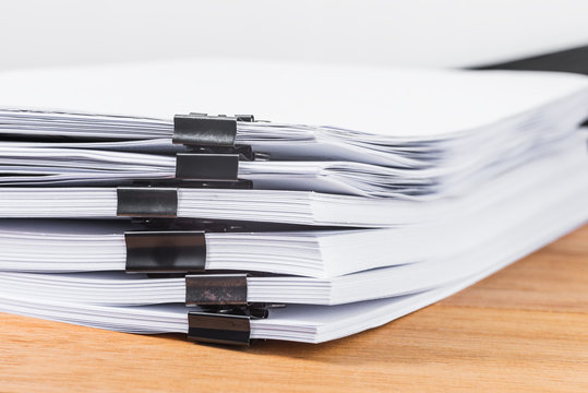 Close-up Binder Clip Pinching Stack Of Papers On Wooden Table