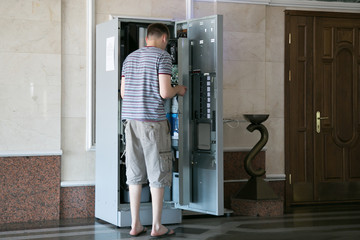 The man is repairing the coffee machine. Repair of a large coffee machine with you at the station.