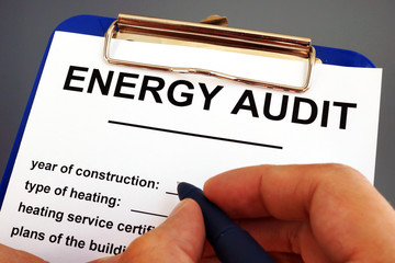 Man filling in energy audit form in a clipboard. - obrazy, fototapety, plakaty
