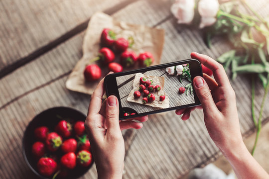 Girl's hands taking photo of breakfast with strawberries by smartphone. Healthy breakfast, Clean eating, vegan food concept