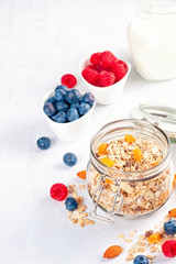 Jar with homemade granola or oatmeal muesli with nuts, dried fruits and fresh berries. Healty diet breakfast, vegan or vegeterian food concept