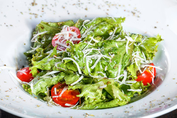 Fresh salad with mixed greens, cherry tomatoes, parmesan cheese on wooden background. Healthy food. Ingredients on table