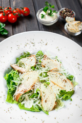 Salad with chicken breast, parmesan cheese, croutons, mixed greens, lettuce on wooden background. Healthy food.