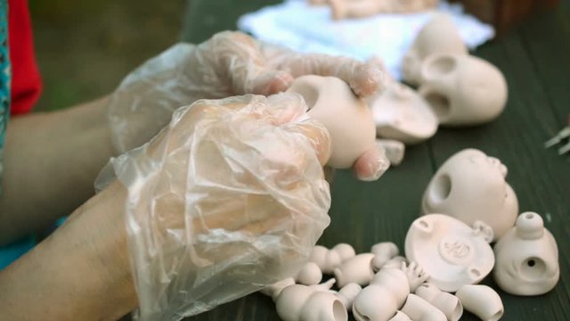 Human hands make dolls of BJD or reborn in the workplace. Processing the workpiece. The concept of the craft of the master manufacturer of dolls. Selective focus. Close-up.