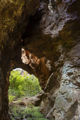 View to small tunnel in big hard rock leading to green forest in Cerro del Hierro, Seviile