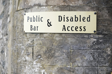Disabled access sign on stone wall at public bar pub entrance