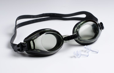 Black glasses for swim on white background, ear plugs