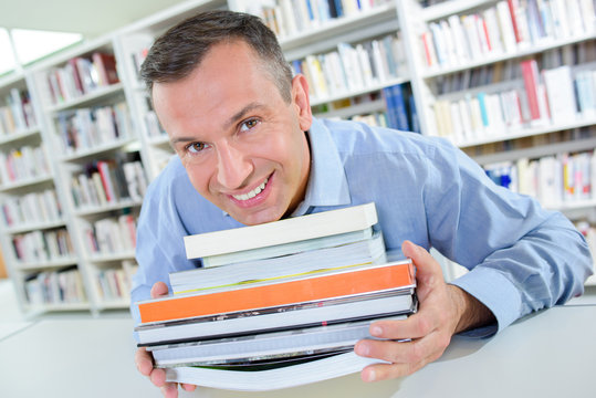 Smiling man holding stack of books