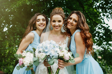 Bride with bridesmaids on the park on the wedding day. 