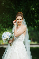 Pretty happy bride in luxury dress with bouquet of roses. 