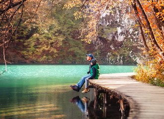 Weekend in autumn park 0 father with son sit on bridge near the mountain lake