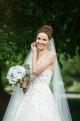 Pretty happy bride in luxury dress with bouquet of roses. 