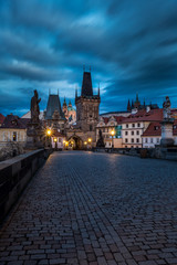 Fototapeta na wymiar View of the Lesser Bridge Tower of Charles Bridge in Prague at sunrise, Czech Republic, Europe. This bridge is the oldest in the city and a very popular tourist attraction.
