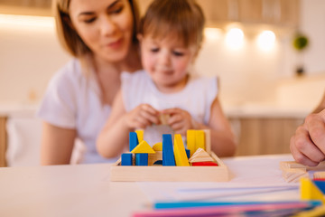 Fototapeta premium Portrait of mother and her daughter who are playing with toys. Blurred image.