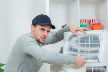 handsome technician installing air-conditioner in building
