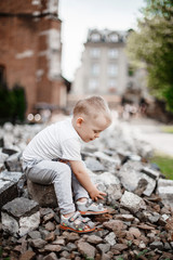 A child with stones. The boy is playing around the historic building. In the courtyard near the church. Little boy