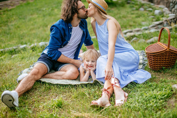 Beautiful happy loving couple on picnic sitting on plaid in field on sunny summer day enjoying and...