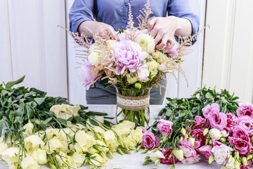 Woman arranging bouquet with pink peonies, roses and yellow dahlias.  tutorial.
