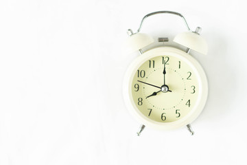 Closeup top view alarm clock on white bed in bedroom for wake up time concept