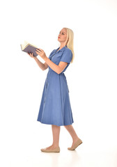 full length portrait of blonde girl wearing blue dress. standing pose holding a book. isolated on...