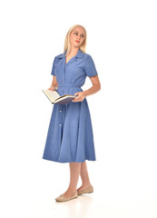 full length portrait of blonde girl wearing blue dress. standing pose holding a book. isolated on white  studio background.