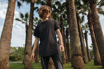 blond curly happy man on street palm at sunset