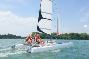 young couple steering a catamaran