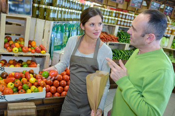 Shop assistant serving tomatoes to male customer