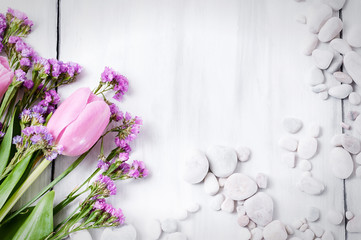 Pink flowers and white pebbles on a white wooden background