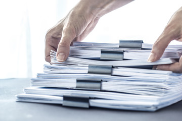 Hands touching office paper. Stacks documents files with black clip. 