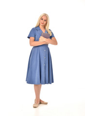 full length portrait of blonde girl wearing blue dress. standing pose holding a book. isolated on white  studio background.