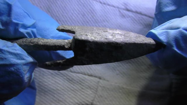 Archeologist inspects authentic ancient arrow head made of metal