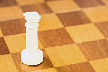 The isolated white chess rook of stone or plastic on the square wood board. The macro shot is made...