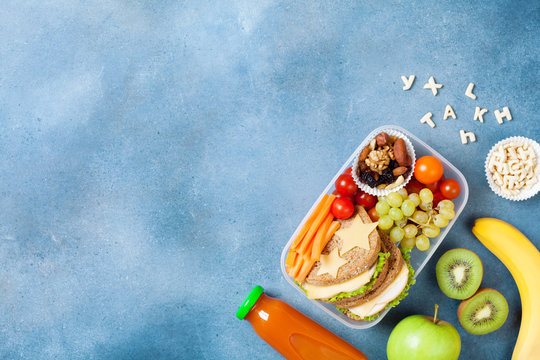 School lunch box with vegetables, fruits and sandwich for healthy snack on table top view.