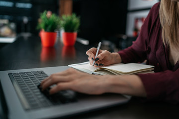 Female hand writing on notebook using pencil notebook at coffee shop. Request for online search in...