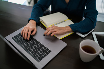 Young woman visits web page by typing search request in network during working at table with cup of...
