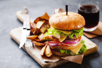 Tasty grilled beef burger with bacon, pickled onion and french fries served on a rustic wooden...