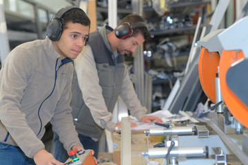 Workmen controlling machinery in factory