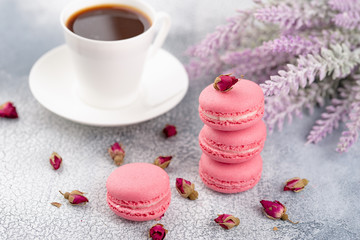 Pink macaroons with dried flower buds and cup of coffee. Pastel colored.