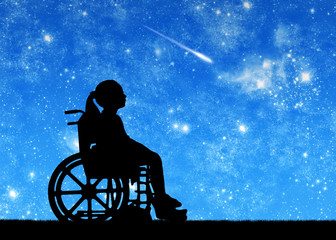 Silhouette of a disabled child girl sitting in a wheelchair looking at the starry sky