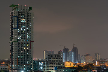 Modern building with a lifting crane, tower crane and building under development construction. 
Construction of a modern high-rise business center at night sky.