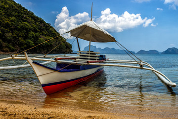 Naklejka na ściany i meble Filipino fishing boat on a background of a cloudy blue sky.