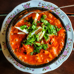 Shashushuli traditional homemade Georgian meat dish with vegetables with spicy sauce in a cast-iron pan frying pan on the background of a wooden table.