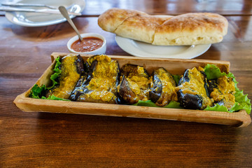 Fried aubergines with nut filling in a bowl of bamboo trunk. Aubergines in Georgian.