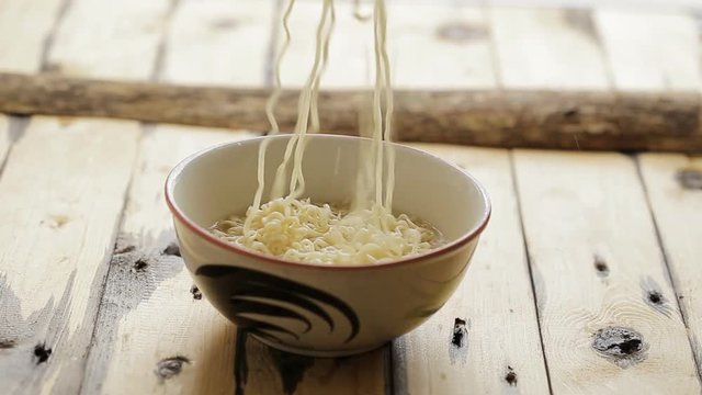 Noodles in bowl on wooden background, selective focus