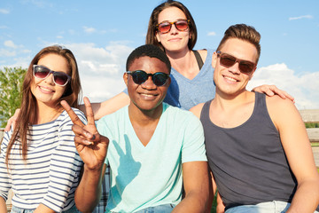 Portrait of young people wearing sunglasses sitting together and smiling