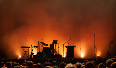 Fototapeta premium pusta scena koncertowa na festiwalu muzycznym, sylwetki instrumentów, mikrofony perkusyjne gitary i tłum ludzi
